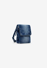 Denim-Crossbody-Tasche mit einem umklappbaren Deckel, geprägtem Logo und silbernem Reißverschluss. Verfügt über eine strukturierte Oberfläche und einen verstellbaren Tragegurt.