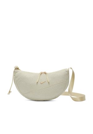 Sac beige texturé en forme semi-circulaire, fermeture éclair, et sangle réglable ; présente un petit logo Nike doré sur le côté.