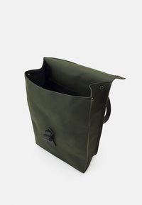 Sac étanche de couleur vert olive avec fermeture enroulable, doté d'un clip à boucle noir et d'une texture lisse. L'intérieur est doublé de tissu sombre.