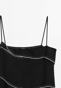 Robe noire sans manches avec fines bretelles et détail en passepoil blanc le long de l'encolure asymétrique et du corsage.