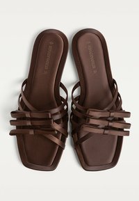 Braune Sandalen mit mehreren überkreuzten Riemen aus glattem Material, mit quadrater Zehenpartie und flacher Sohle. Größe ist mit 37 gekennzeichnet.