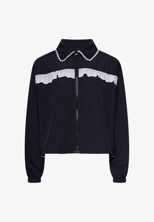 Schwarze, langärmelige Jacke mit Reißverschluss, weißer Spitzenverzierung über Brust und Kragen, elastischen Bündchen und leicht gekürztem Saum.