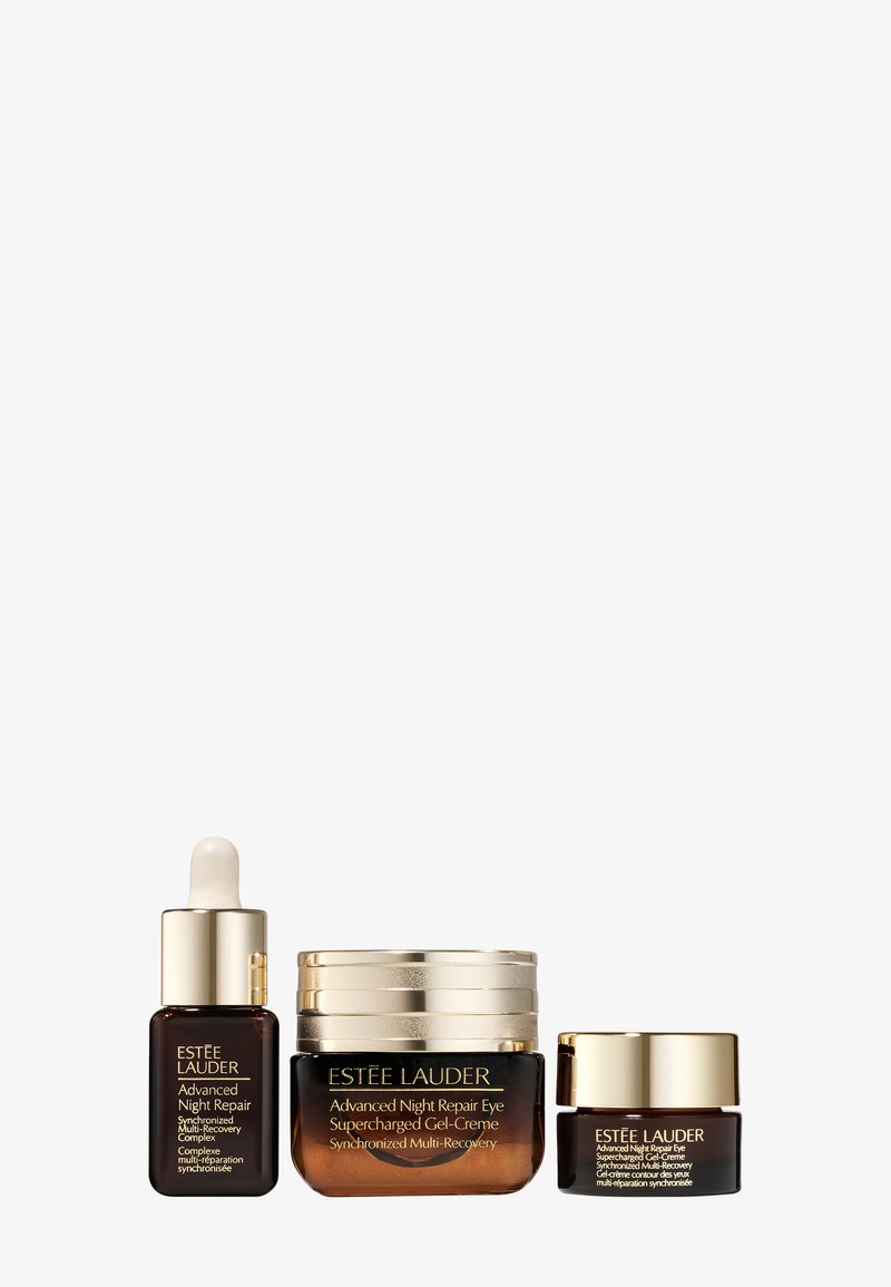 Trois produits de soin Estée Lauder : un flacon à pipette marron, un pot de crème avec des accents dorés et un petit pot de crème, tous dotés de designs élégants.