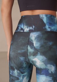 Leggings de cintura alta con estampado abstracto multicolor en tonos azules y negros. Tejido suave y elástico con costuras planas para mayor comodidad.