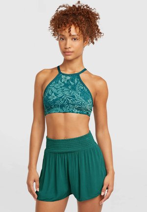 Turkoois cropped top met bloemenpatroon en halternek, gecombineerd met losse turkooizen shorts met een gerimpelde taille. Beide gemaakt van lichtgewicht stof.
