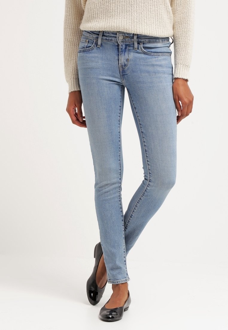 Jeans skinny bleu clair avec une fermeture classique à bouton et à zip, dotés de poches avant et d'une texture denim douce. Accompagnés de ballerines noires.