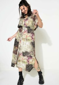 Sukienka koszulowa zapinana na guziki w wzór tie-dye w odcieniach zieleni, różu i czerni. Posiada krótkie rękawy, elastyczny pas i boczne rozcięcia, noszona z czarnymi botkami.
