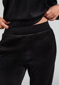 Musta, pehmeä veluurikangasvaatteet korkean vyötärönauhalla, jossa on sileä pinta ja saumatonta muotoilua vyötäröllä.