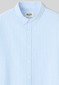 Chemise bleu clair à manches longues avec des rayures verticales blanches, un col évasé, et six boutons sur le devant étiquetés taille L confort BZB.