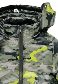 Camouflage-patterned padded jacket with black zipper and hood featuring snap button closure on one side.
