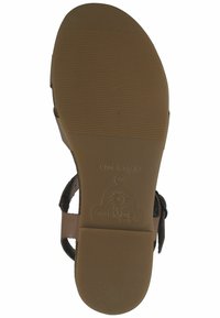 Tanfarbene Sandalensohle mit strukturiertem Grip und leichtem Fußgewölbe. Markierungen zeigen "MADE IN SPAIN" und ein Sonnenlogo. Einfaches Design mit minimalen Akzenten.