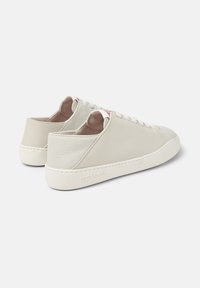 Sneaker in pelle bianca con finitura liscia, punta arrotondata, chiusura frontale con lacci piatti e dettagli testurizzati sul tallone. Marchio discreto di lato.