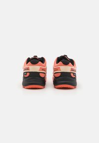 Salomon running shoes with a black, orange, and beige color scheme. Textured mesh upper, cushioned heel, and flexible rubber sole.