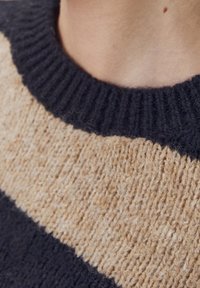 Wollen trui met een zwart en beige horizontaal streep patroon, voorzien van een ribbelkraag en een zachte, gestructureerde afwerking.