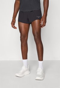 Svarte treningsshorts med et stilrent design, som har en subtil reflekslogo foran. Stylet med hvite sneakers og sokker.