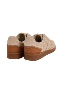 Sneaker in suede beige con suole in gomma marrone testurizzate, caratterizzate da accenti cuciti e un design a profilo basso. Il tallone presenta una texture a motivo.