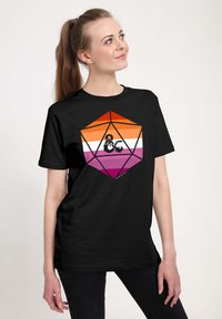 Sort t-shirt med et farverigt geometrisk design med orange, hvidt og pink striber, og en sort drage motiv i midten.