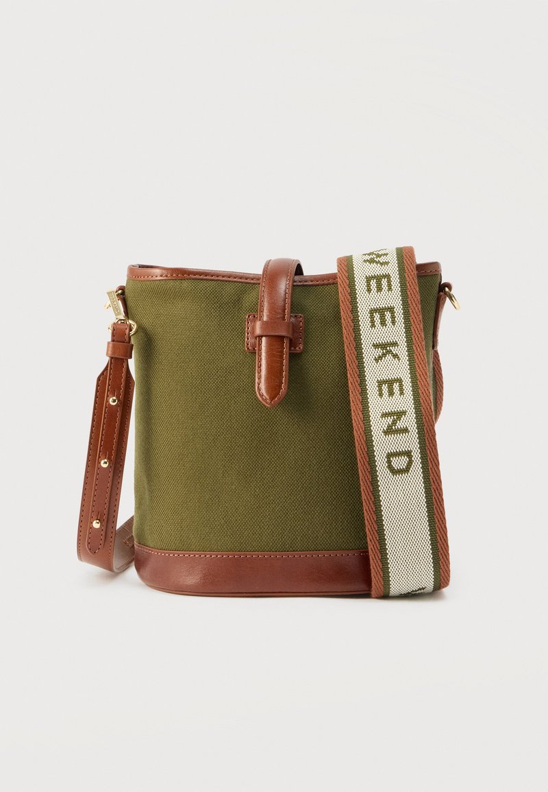 Πράσινη τσάντα κάδος από καμβά με καφέ δερμάτινη επένδυση και ρυθμιζόμενο ιμάντα που φέρει το κείμενο "WEEKEND" σε υφασμάτινη ταινία.