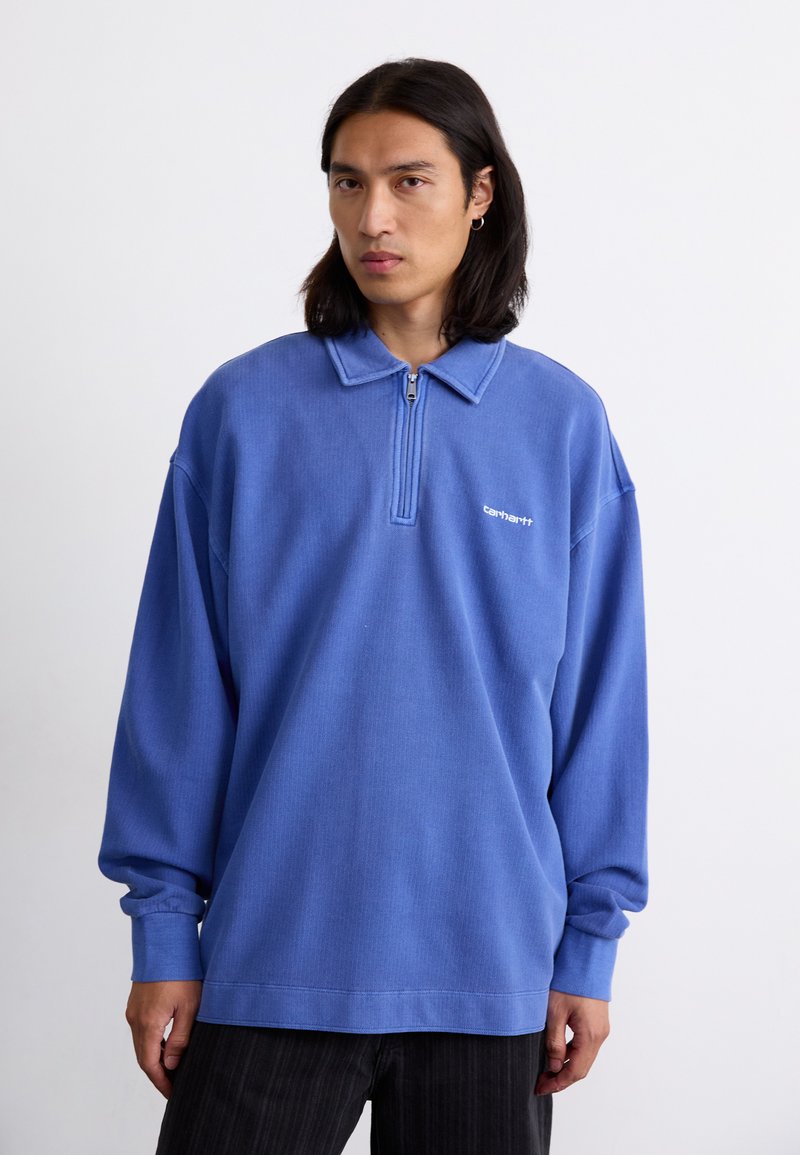 Blue zip-up sweatshirt with a collar, made of textured fabric. Features a small white logo on the chest and long, loose sleeves.