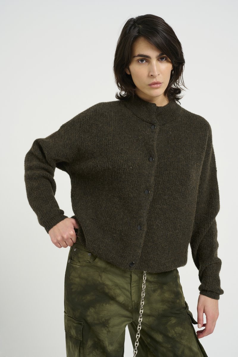 Dark green knit cardigan with a high collar, black buttons, and relaxed fit; worn over tie-dye olive green cargo pants featuring pockets.