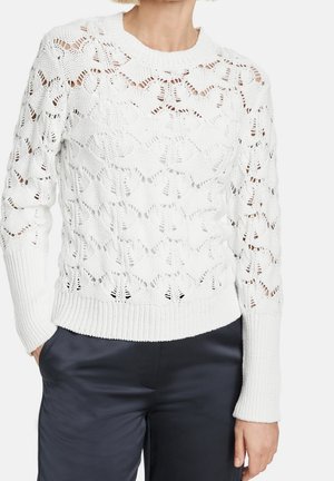 Pull blanc en maille avec un motif ajouré présentant des cœurs, des poignets et un ourlet côtelés, et un col rond. Texture lisse et léger.