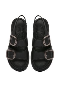 Sandalias de cuero negro con doble hebilla ajustable, diseño abierto por detrás, suela plana y textura suave con detalles de costura.