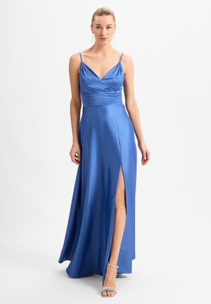 Maxikleid aus blauer Satin mit tiefem V-Ausschnitt, gerafftem Oberteil, dünnen Trägern und einem seitlichen Schlitz, kombiniert mit silbernen Riemchenheels.