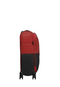 Red and black rolling suitcase with a textured fabric surface, a zippered compartment, and four spinner wheels for easy maneuverability.