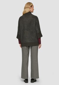 Oversized donkergrijze pullover met een hoge kraag en driekwartmouwen, gestructureerde stof, gecombineerd met lichtgrijze wijde broek.