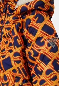 Färgglad vadderad jacka med ett livfullt mönster i orange och blått, med en glansig yta. Har en logotypmärke på ärmen.