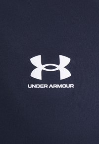 Navyblauer Sportstoff mit einem weißen Under Armour-Logo und einem stilisierten Doppel-"U"-Design, das zentriert unter dem Markennamen platziert ist.