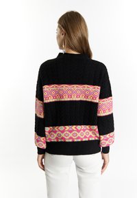 Pulover negru din tricot cu un model geometric vibrant de dungi roz, galbene și violet. Croi lejer, cu manșete și tiv ribbed.