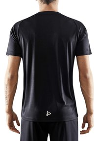 Camiseta atlética negra de mangas cortas, fabricada en un tejido ligero y suave. Presenta un detalle de logo reflectante cerca del dobladillo.