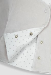 Chaqueta de forro polar gris suave con forro blanco que presenta un estampado de estrellas. Cierre con broches de herrajes plateados. Textura lisa en toda la prenda.
