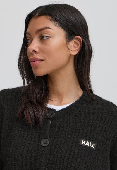 Cardigan negru tricotat, cu guler rotund, două butoane mari și o etichetă mică de marcă pe partea stângă. Material texturat.