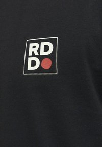 Juodas audinio marškinėliai su balta kvadratine logo, kurioje užrašyti storais rašmenimis "RD" ir "DO", be to, yra raudono taško akcentas.