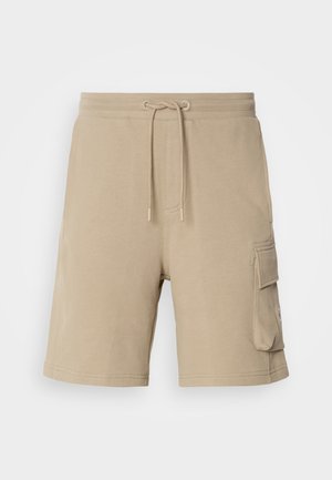 Pantaloni cargo beige realizzati in tessuto morbido, con vita regolabile mediante cordoncino e tasche laterali. Design semplice, lunghezza al ginocchio, dettagli di cucitura minimi.