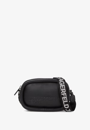 Fekete bőr keresztpántos táska ovális formával, dombornyomott logóval és kontrasztos csíkozott pánttal, amelyen a "KARL LAGERFELD JEANS" felirat található.