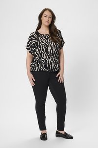 Černá a krémová vzorovaná košile s krátkým rukávem a uvolněným střihem, kombinovaná s černými slim-fit kalhotami a černými mokasíny. Hladký textilní materiál.
