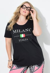 Černé tričko s nápisy "MILANO" a "ITALIA" v bílé barvě, s akcenty v zelené a červené. Krátké rukávy, kulatý výstřih a uvolněný střih.