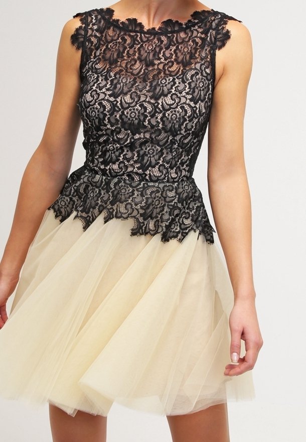 Robe sans manches avec un corsage en dentelle florale noire et une jupe en tulle beige, avec un ourlet en dentelle festonné à la taille.