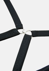 Drie zwarte elastische banden met de tekst "BODY" komen samen en verbinden zich bij zilverkleurige metalen ringen tegen een lichte achtergrond.