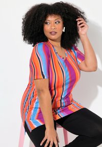 Túnica de cuello en V a rayas arcoíris en vibrante naranja, púrpura y azul, hecha de un tejido suave con un corte relajado y aberturas laterales para mayor comodidad.