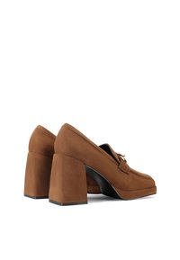 Scarpe in suede marrone con tacco a blocco e punta rotonda, dotate di un accento dorato sulla tomaia, caratterizzate da una superficie texturizzata e un silhouette robusta.