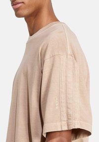 Beige cotton t-shirt with a relaxed fit, featuring a crew neckline, stitched details, and embroidered "ALL SZN" on the sleeve.
