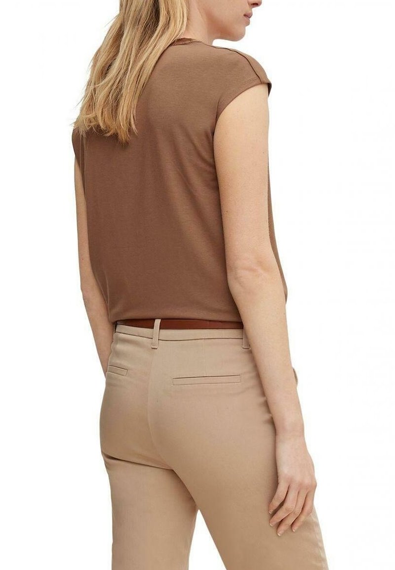 Haut marron à manches courtes, avec une coupe décontractée, associé à un pantalon beige clair avec une taille standard et des poches arrière.