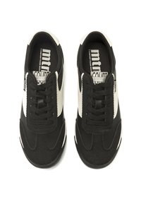 Zapatillas negras y blancas con parte superior de tejido texturizado, puntera redonda, rayas en contraste y cordones planos. La suela ofrece agarre y amortiguación.