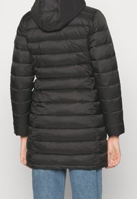 Abrigo acolchado negro con capucha, con costuras horizontales, mangas largas y un diseño hasta la rodilla. El material parece suave y brillante.