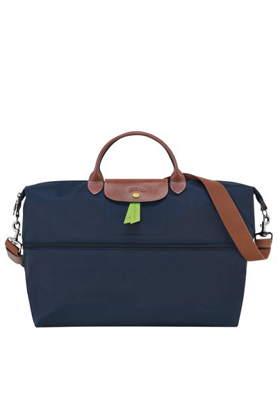 Navy blue nylon bag with brown leather accents, top handles, and a detachable shoulder strap; features a zipper pocket and green tag detail.