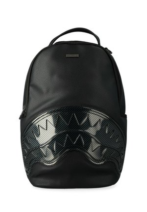 Mochila negra texturizada con un patrón brillante de fibra de carbono en formas zigzagueantes y afiladas que se asemejan a dientes de tiburón en el bolsillo delantero.